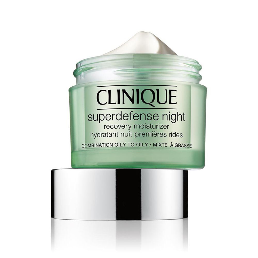 Een geopend Clinique Superdefense nachtcrème potje met het zilveren deksel ernaast.