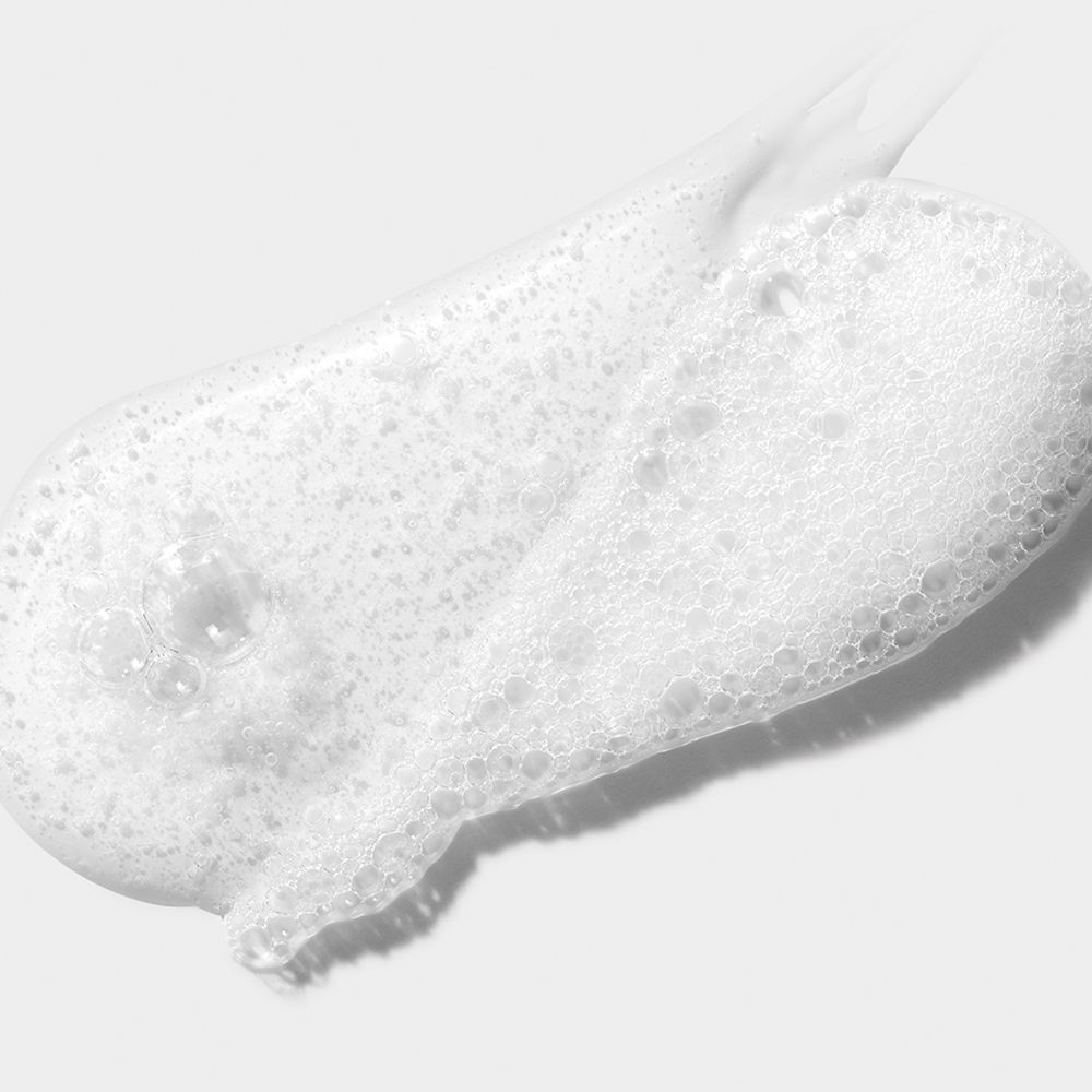 Une traînée de gel nettoyant blanc et moussant avec des bulles.