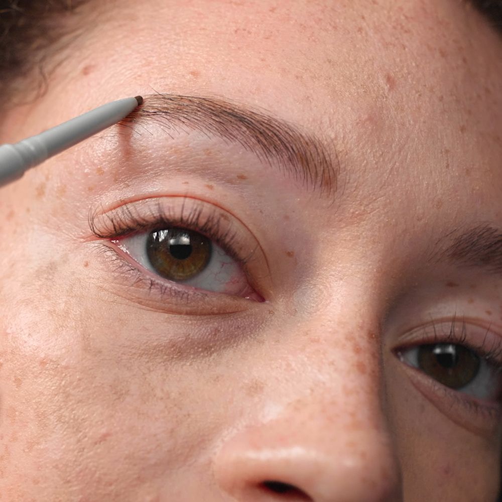 Une main utilise un crayon à sourcils CLINIQUE Quickliner pour définir un sourcil.