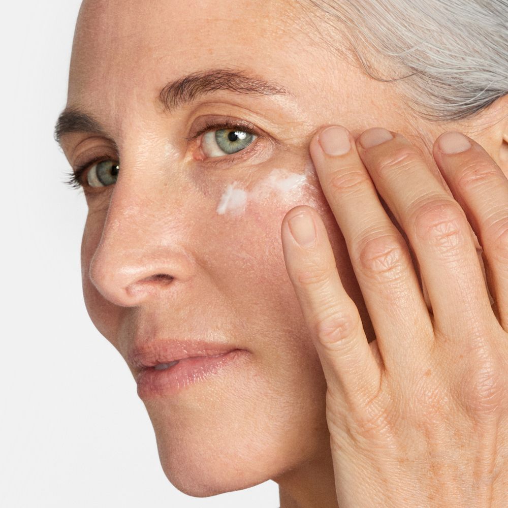 Een vrouw brengt Clinique Smart Clinical Repair oogcrème aan.