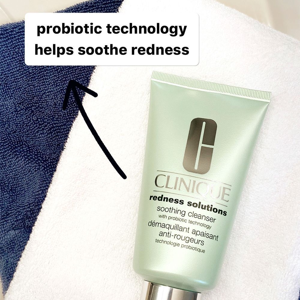 Un tube de nettoyant apaisant CLINIQUE Redness Solutions à côté de serviettes bleues et blanches.