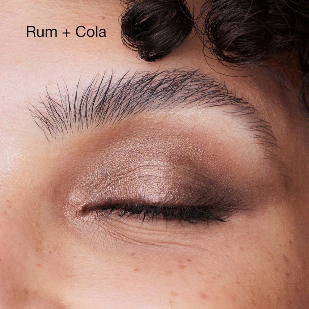 Oogmake-up in bruine en rode tinten, met tekst "Rum + Cola".