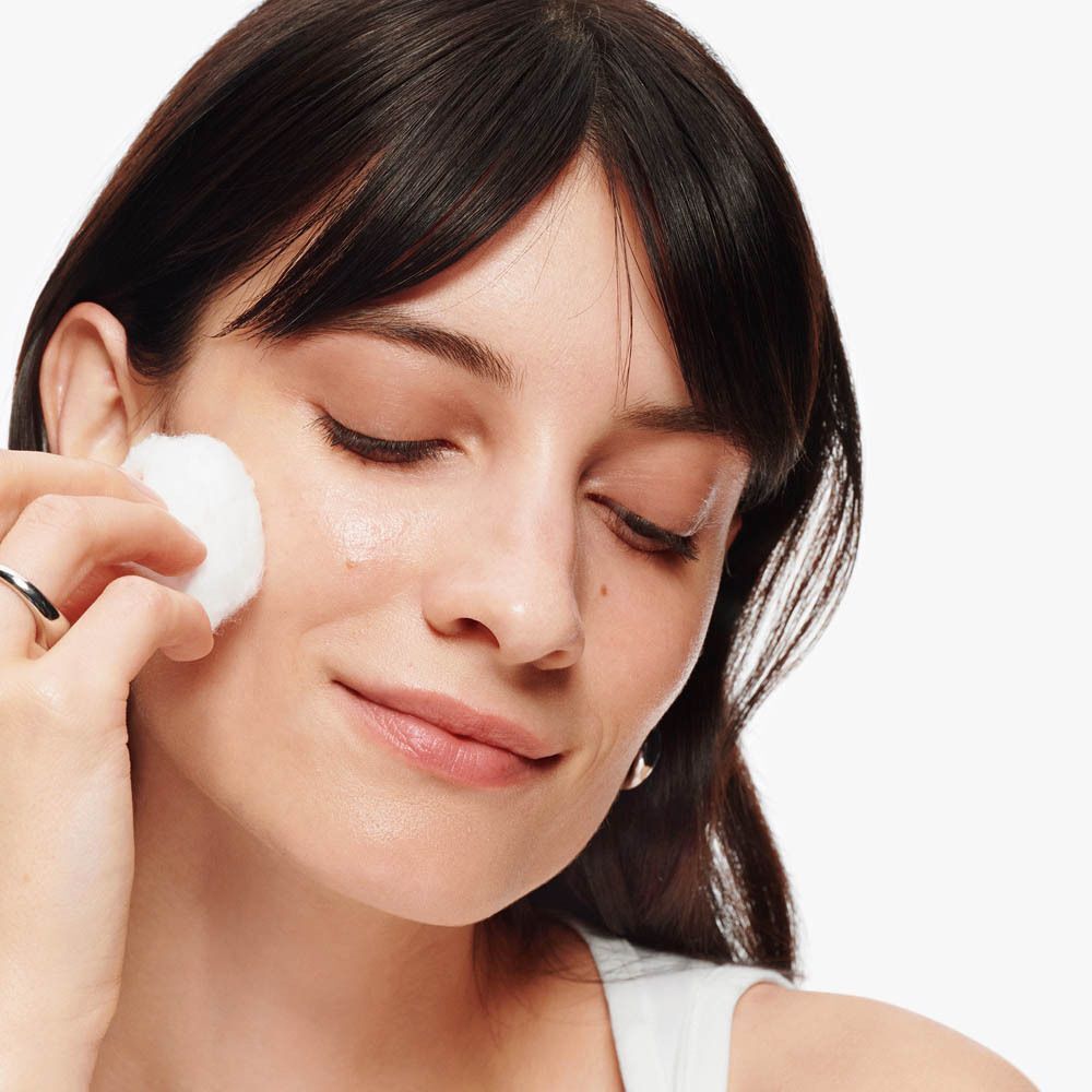 Femme appliquant un coton sur sa joue