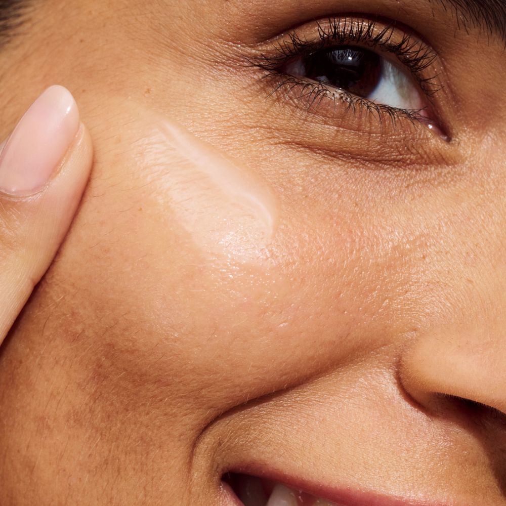 Gros plan d'une personne appliquant le produit sur sa peau. Le produit est visible.