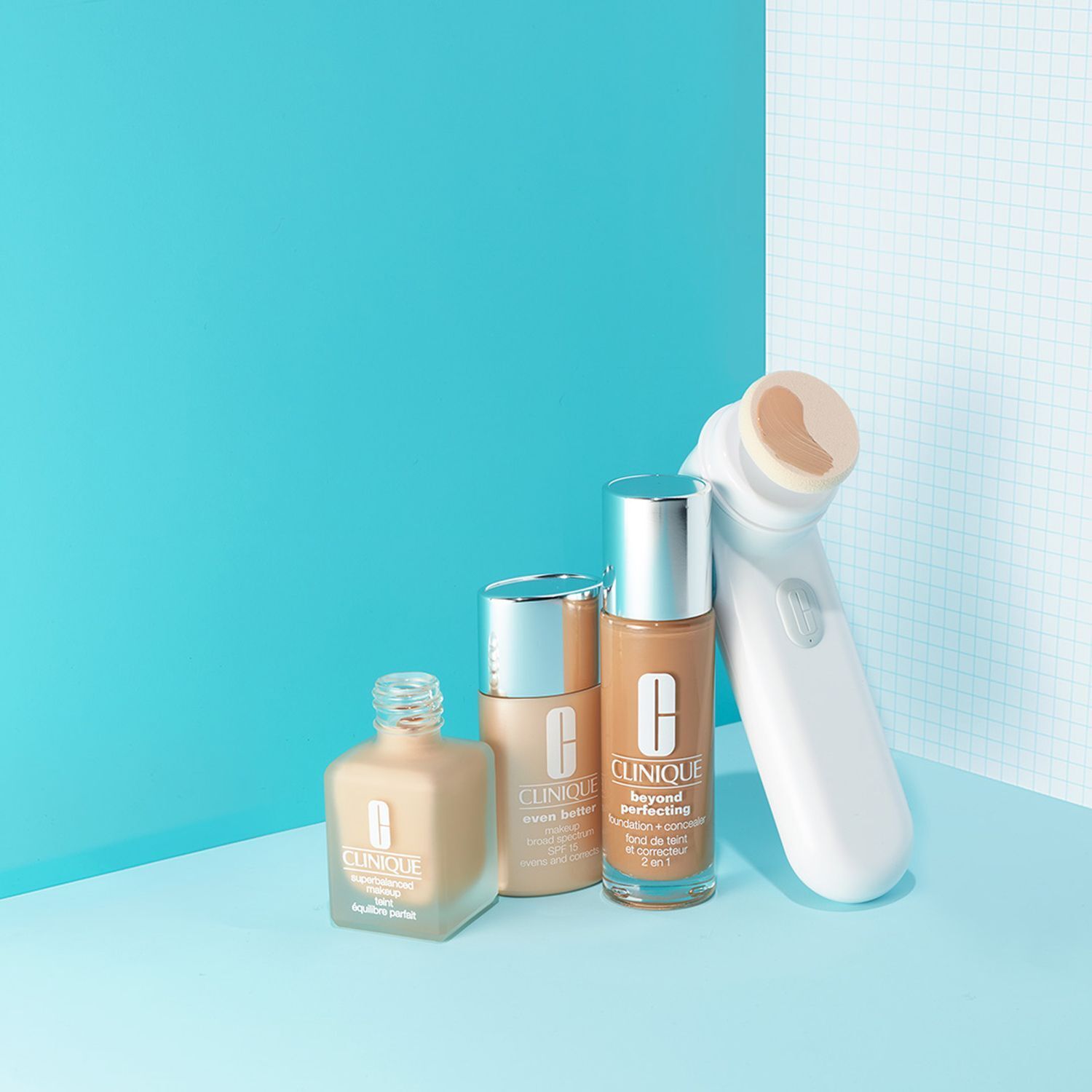 Drie flacons Clinique Beyond Perfection Make-Up en een huidverzorgingsapparaat.