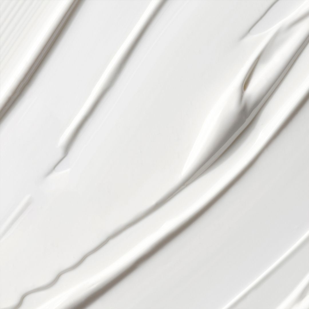 Gros plan de crème blanche. Texture avec stries visibles. Pas de nom de produit.