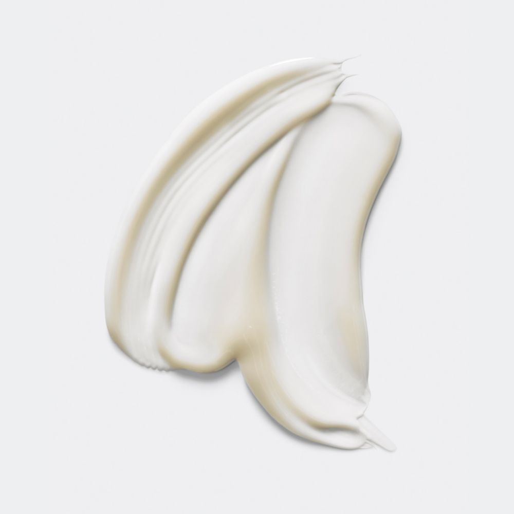 Gros plan d'un produit crèmeux étalé sur une surface blanche. La texture est lisse.