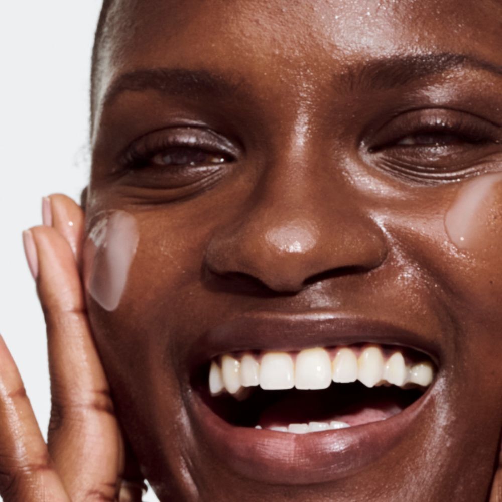 Gros plan d'une personne appliquant le produit sur sa peau. Un liquide transparent est visible.