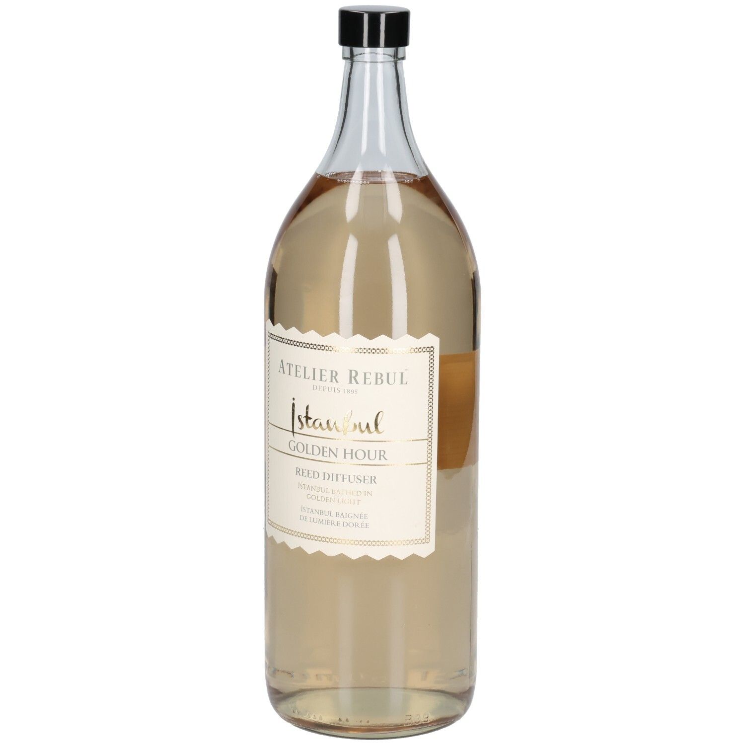 Grande bouteille en verre transparent avec bouchon noir. Étiquette avec texte doré : Atelier Rebul Istanbul Golden Hour Reed Diffuser.