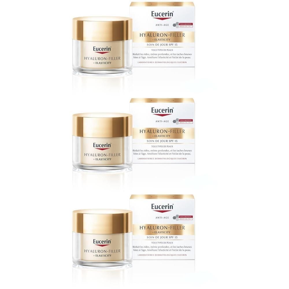 Trois pots de Eucerin Hyaluron-Filler + Elasticity Soin de Jour SPF15 et emballages. Couvercles dorés, emballage blanc.