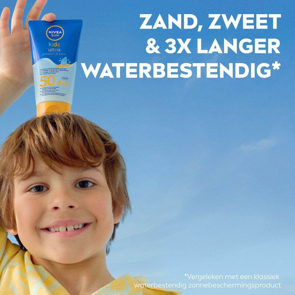 Een kind krijgt zonnecrème op de arm aangebracht. Kind draagt een geel overhemd. Blauwe achtergrond.