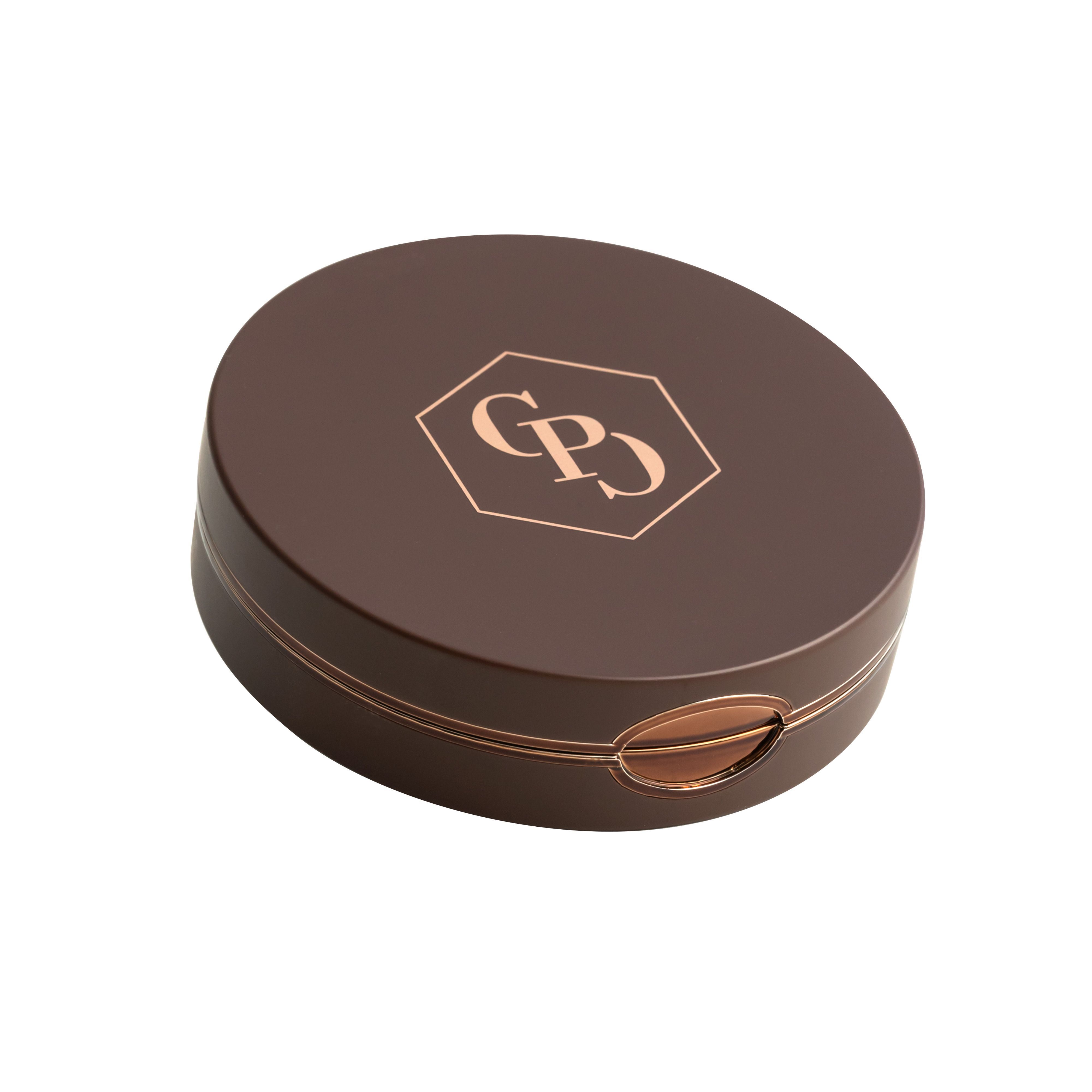 Gesloten, ronde bronzer compactpoeder hoes. Bruine kleur, goudkleurig logo. Gouden rand.