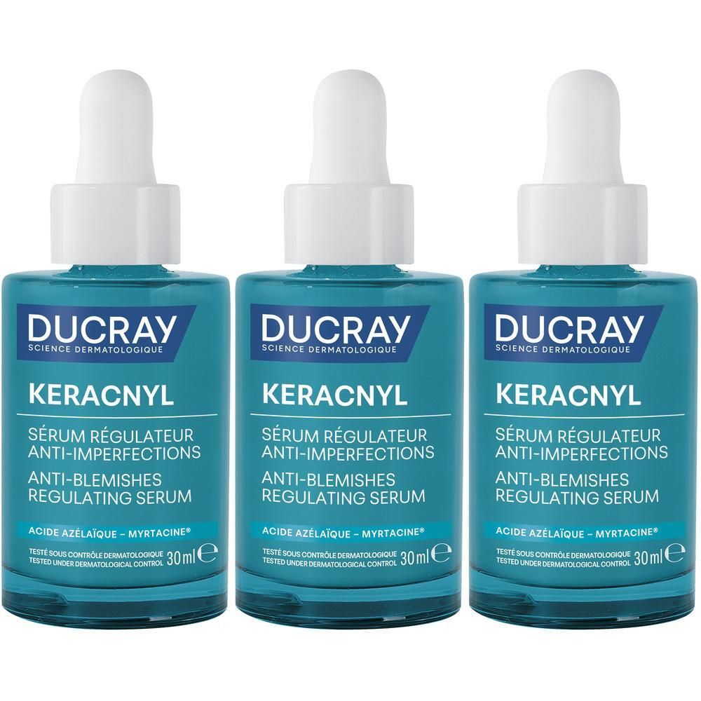 Trois flacons de sérum Ducray Keracnyl. Flacons en verre bleu avec bouchon et pipette blancs. Texte et nom.