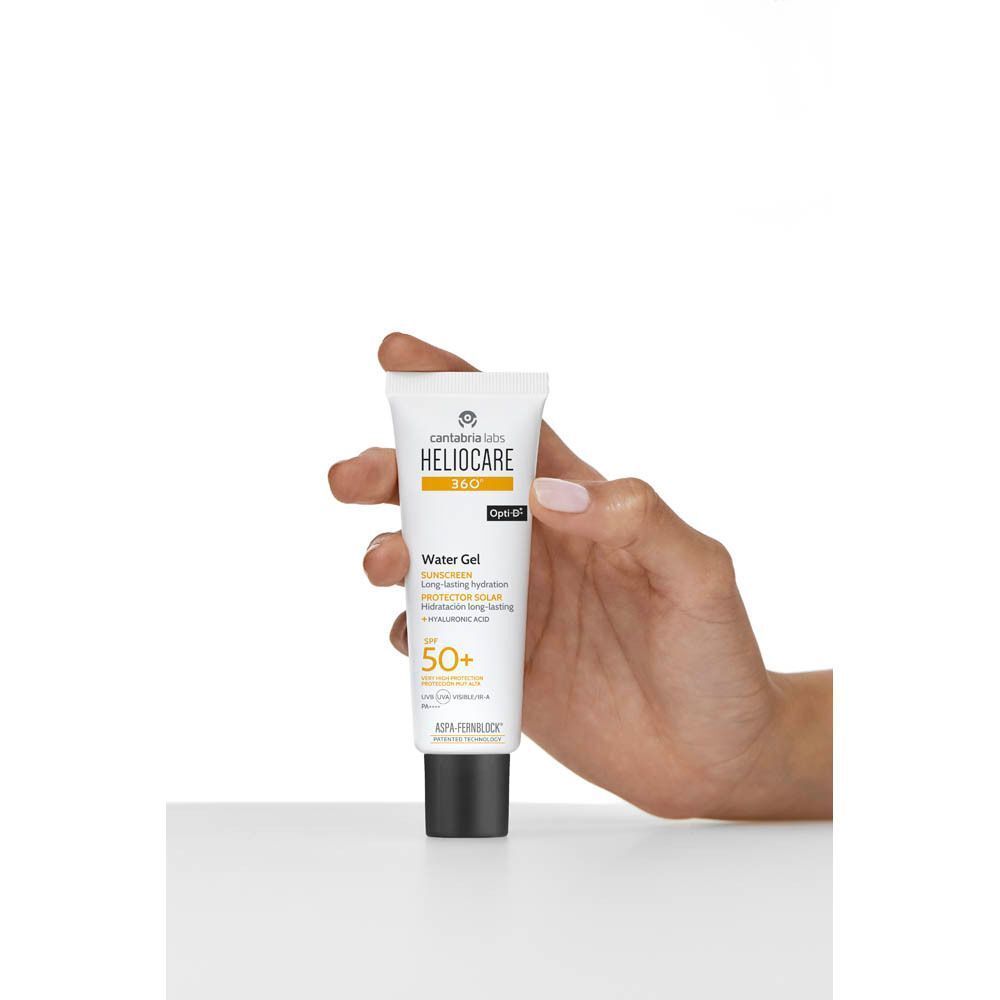 Hand houdt tube Heliocare 360° Water Gel SPF50+. Witte tube met zwarte dop. Tekst: Heliocare 360°, Water Gel, SPF50+.