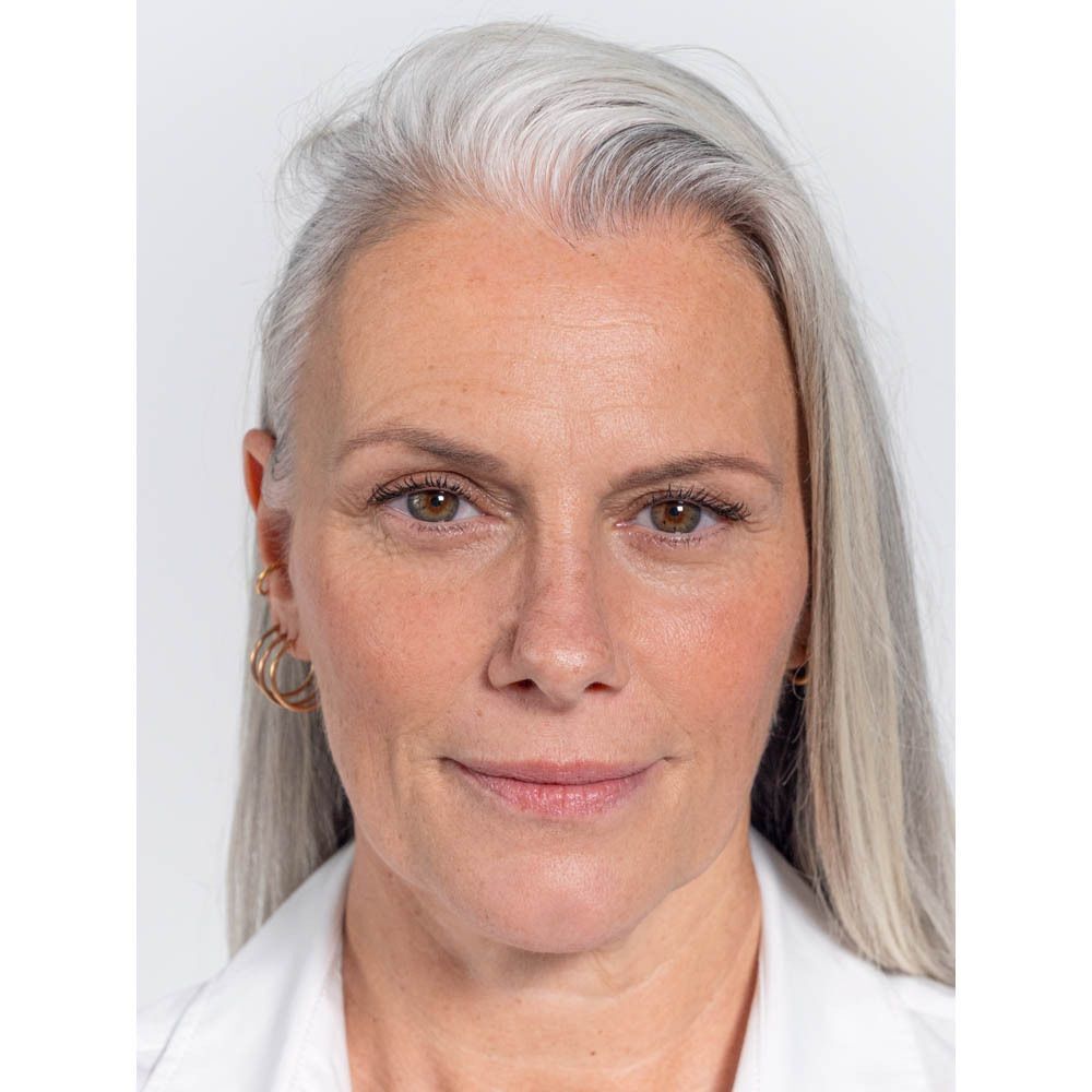 Portrait d'une femme aux cheveux gris. Créoles dorées. Maquillage naturel.