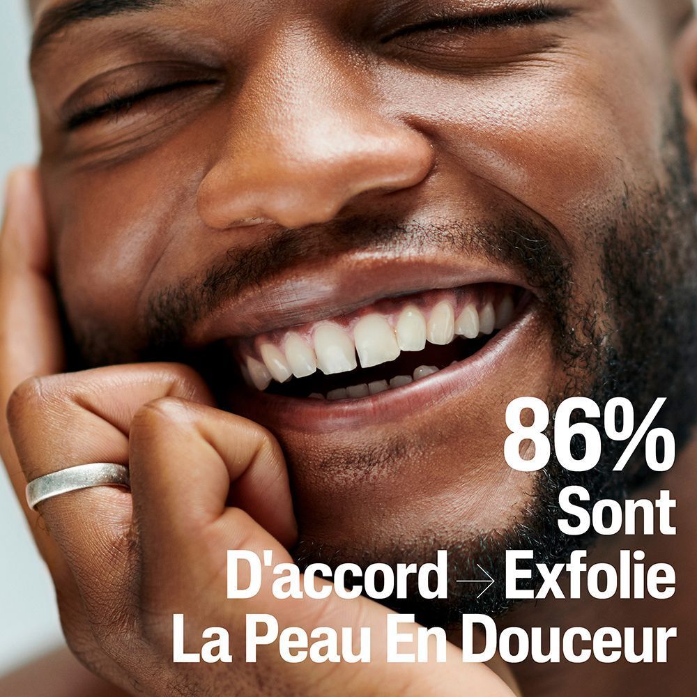 Gros plan d'un homme souriant. Texte: 86% sont d'accord pour exfolier en douceur. Homme avec barbe et bague argentée.