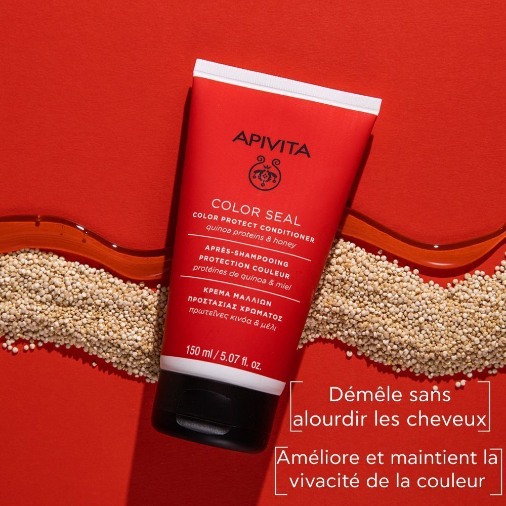 Tube rouge Apivita Color Seal Après-Shampooing. Inscriptions et logo visibles. Grains de quinoa et rayon de miel en arrière-plan.