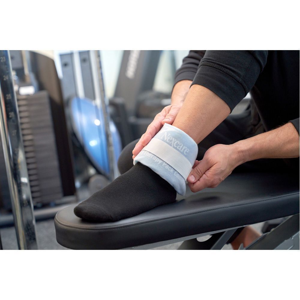 Personne avec un Nexcare ColdHot Therapy Pack à la cheville. Produit avec fermeture velcro.