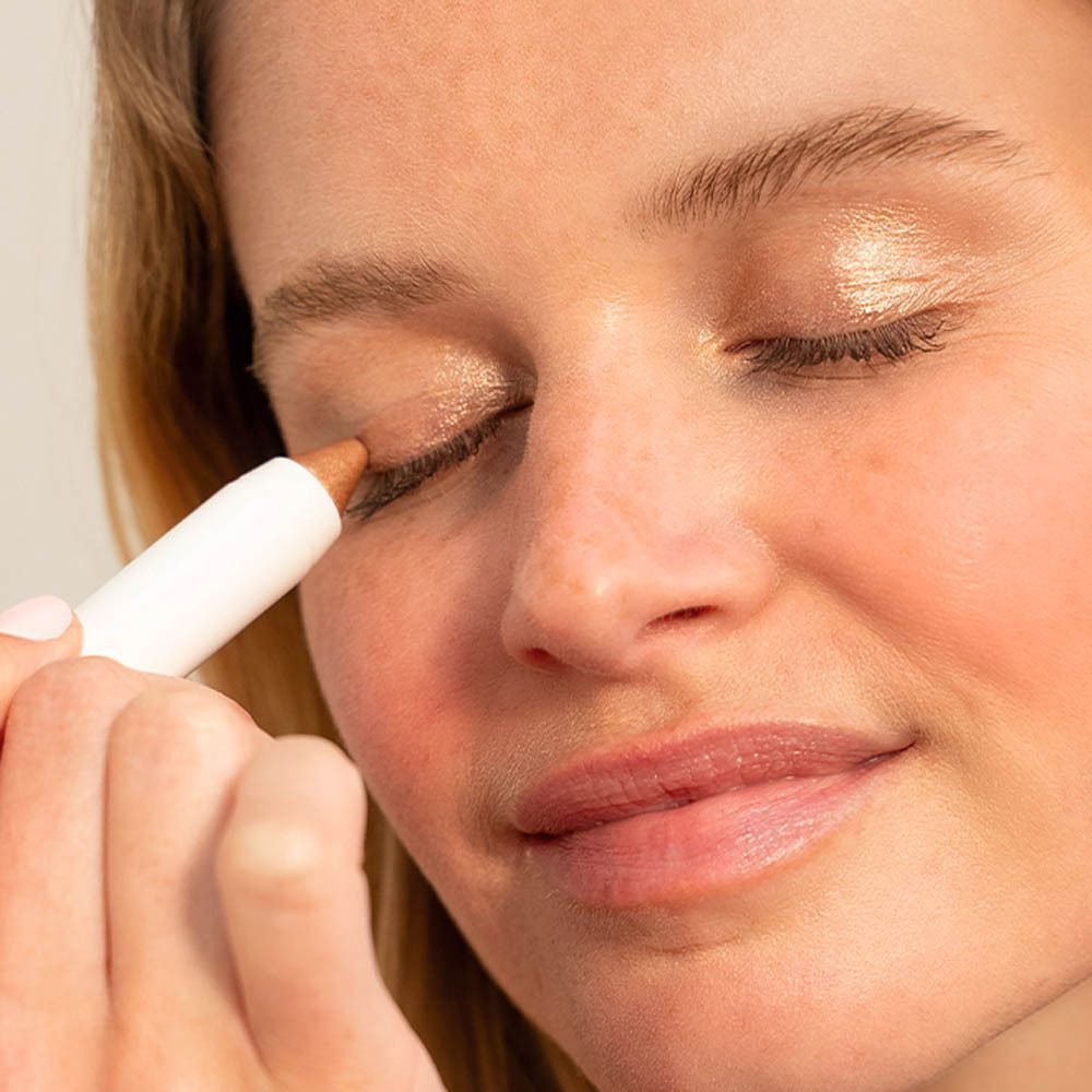 Vrouw met gouden oogschaduw. Witte stift in gebruik.