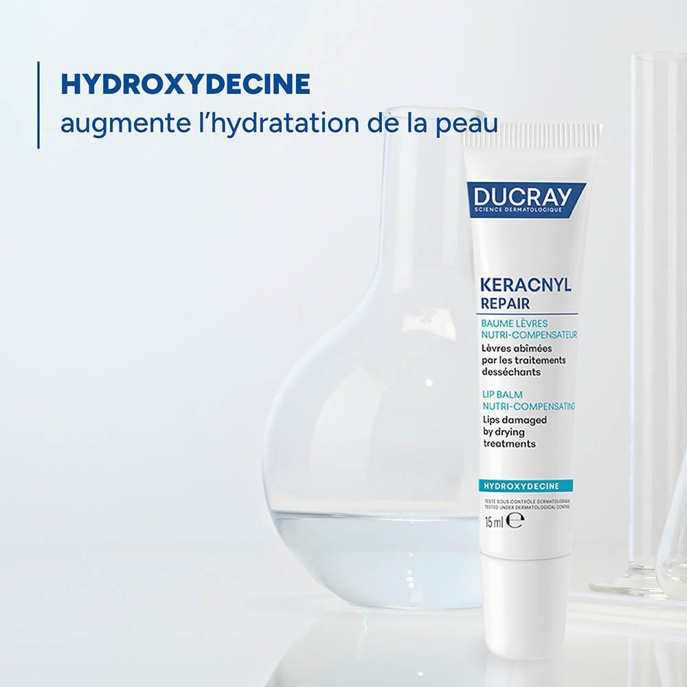 Un baume à lèvres Ducray Keracnyl Repair en tube de 15 ml, à côté d'équipements de laboratoire.
