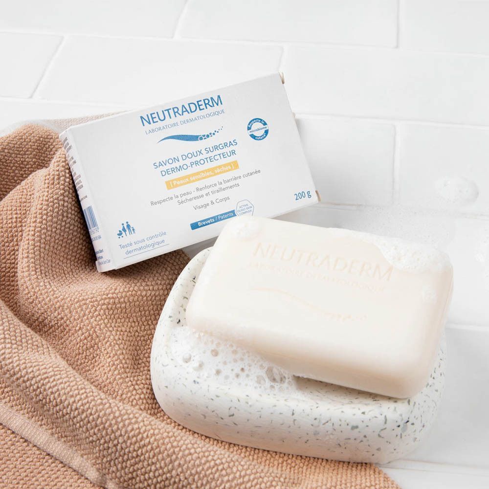 Neutraderm Dermo-Protecteur Savon Doux Surgras zeep en verpakking op handdoek en zeepbakje. Tegelachtergrond.