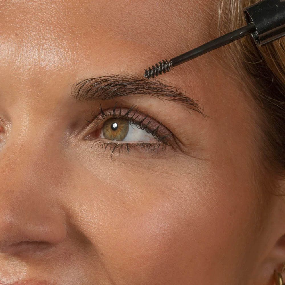 Close-up van een oog en wenkbrauw die met een borstel wordt bewerkt.