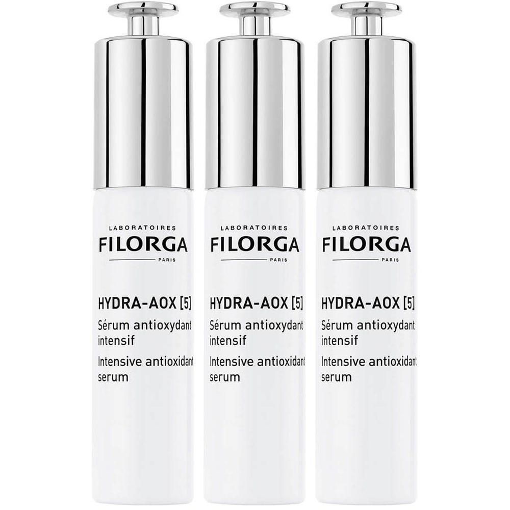 Trois flacons de sérum Filorga HYDRA-AOX [5]. Flacons blancs avec bouchons argentés. Texte: HYDRA-AOX [5] Sérum antioxydant intensif.