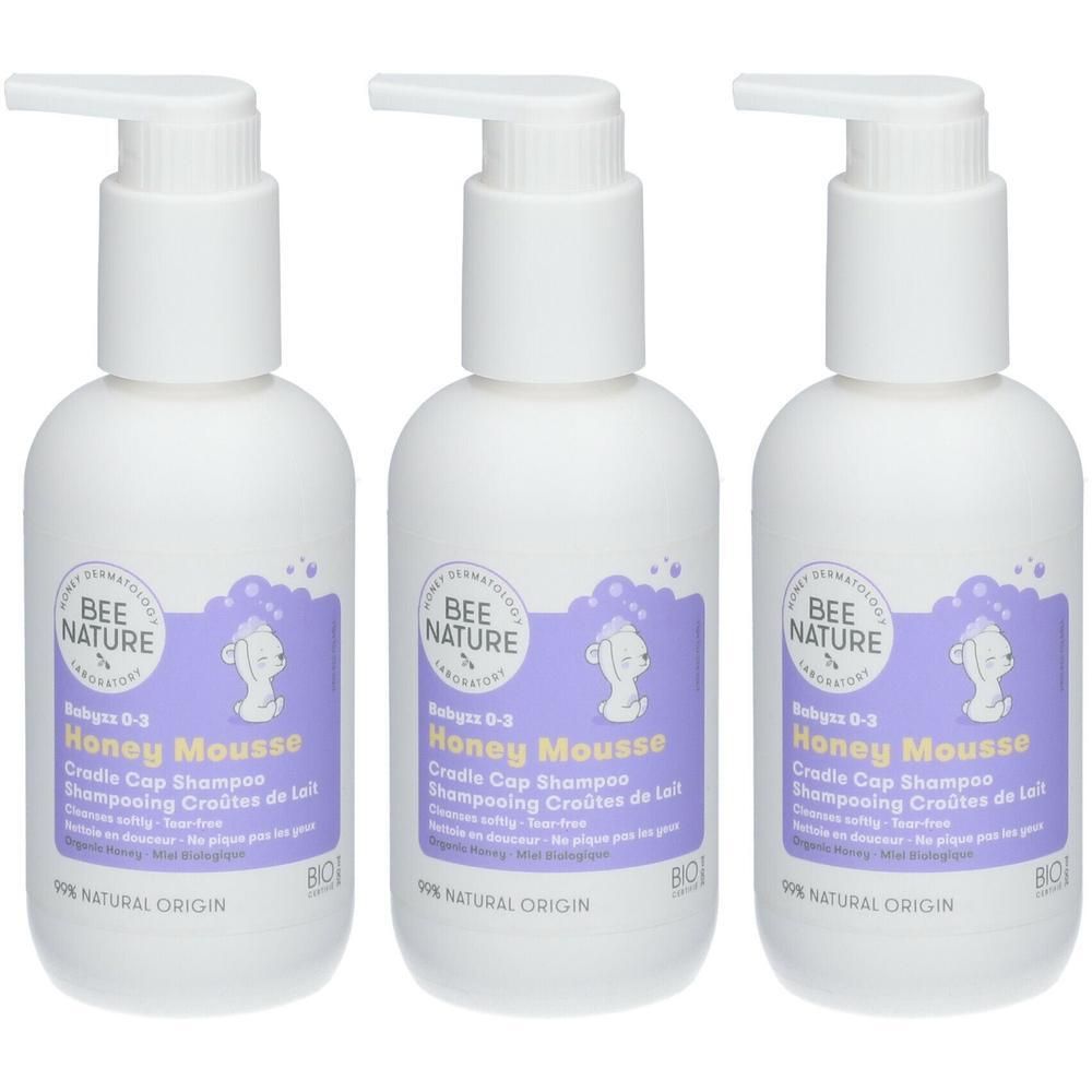 Drie witte flessen met pomp. Etiketten met productnaam en logo. Opschrift: Honey Mousse, Shampoing Croûtes de Lait.