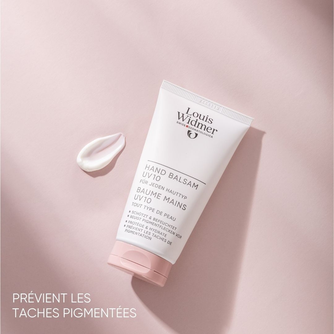Un tube de baume pour les mains avec bouchon rose et une goutte de crème. Inscription: Hand Balsam UV10.