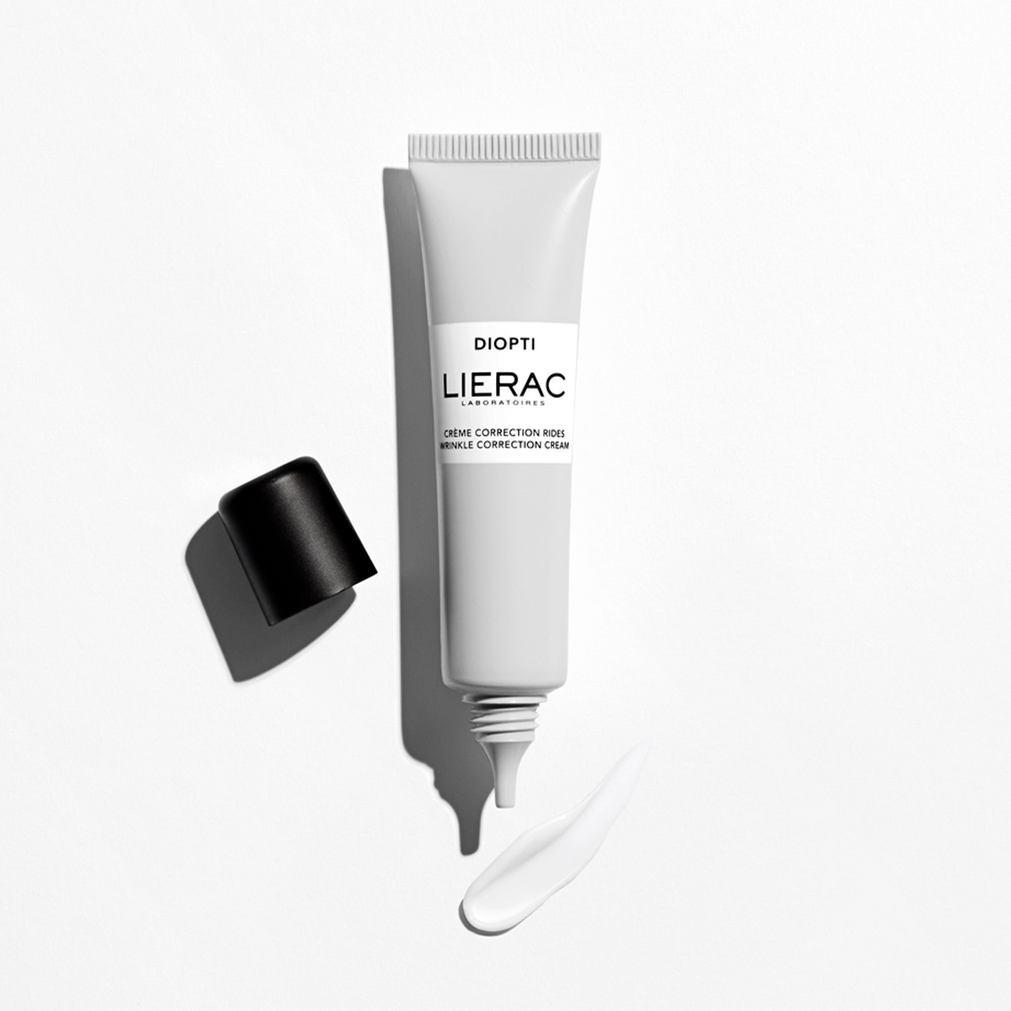 Tube Lierac Diopti Crème Correction Rides, ouvert. Bouchon noir à côté. Filet de crème. Texte: Diopti, Lierac Laboratoires, Crème Correction Rides.