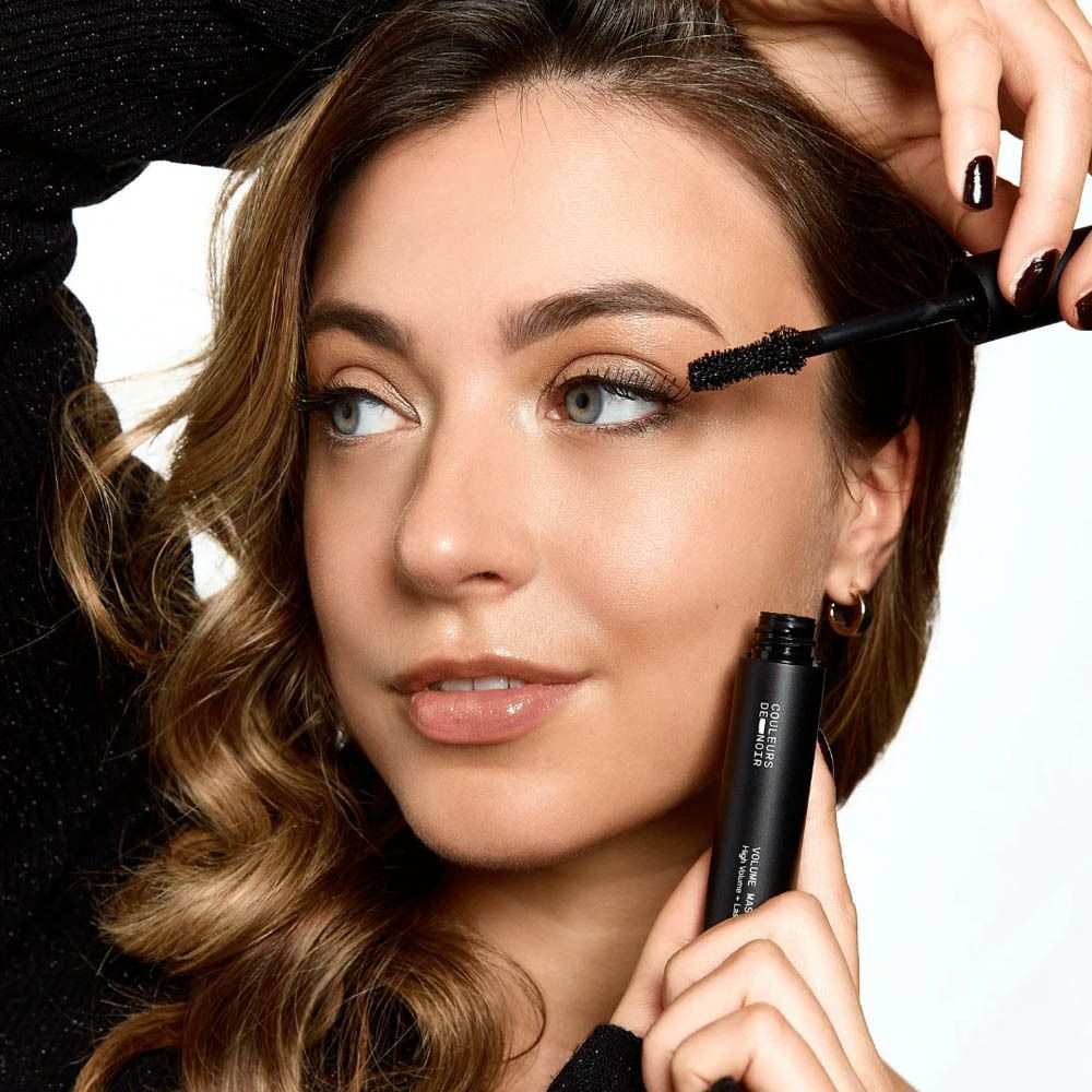 Femme avec applicateur de mascara. Nom du produit visible.