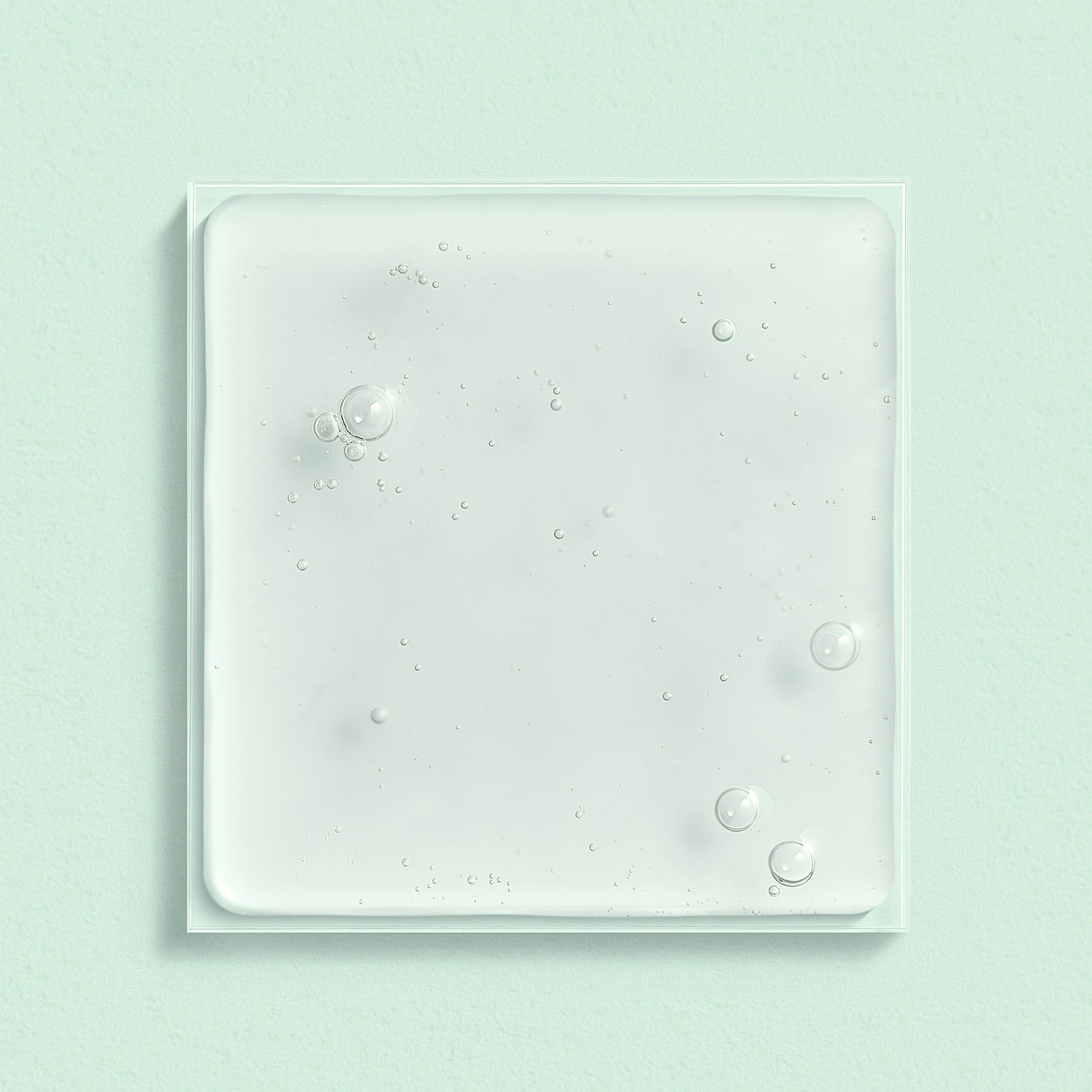 Vierkant staal van Lierac La Lotion Hydratante. Heldere, lichtgroene vloeistof met bellen. Op witte achtergrond.