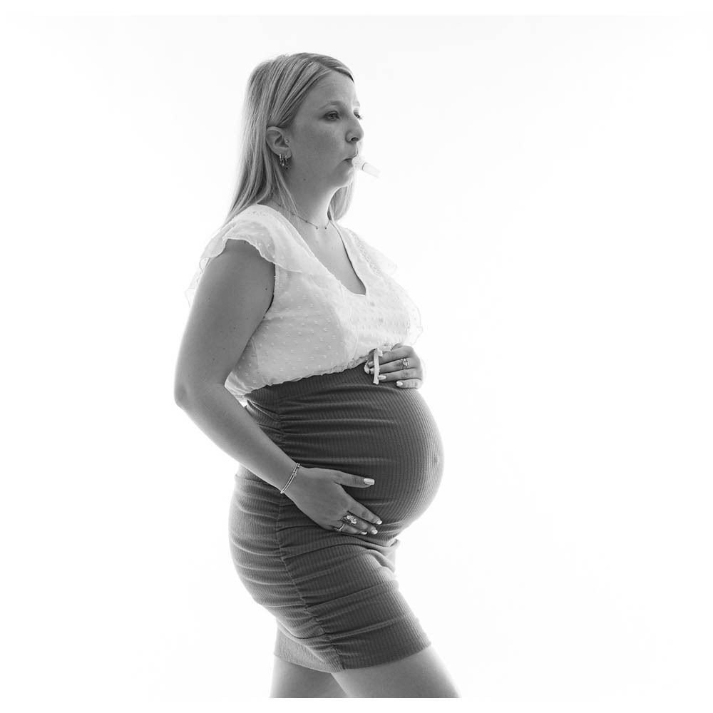 Femme enceinte avec STIMED Winner Flow dans la bouche. Elle tient son ventre, le produit est positionné dans la bouche.