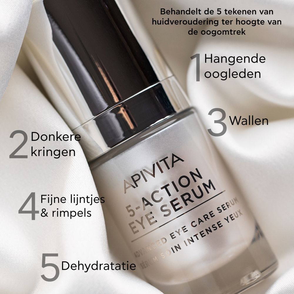 Apivita 5-Action Eye Serum op witte stof. Opschrift: 5-Action Eye Serum, Advanced Eye Care Serum. Markering van de 5 tekenen van huidveroudering.