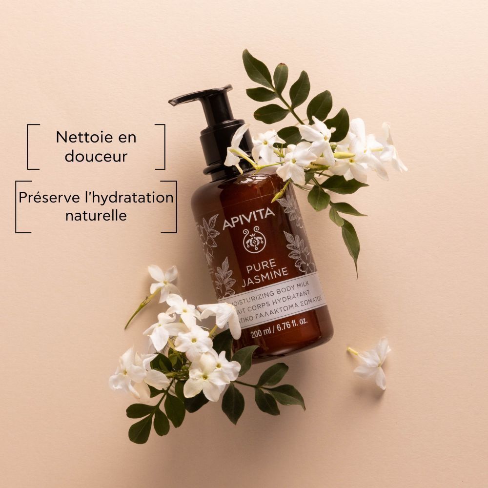 Flacon Apivita Pure Jasmine Lait Corps Hydratant entouré de fleurs de jasmin. Texte: Nettoie en douceur, Préserve l'hydratation naturelle.