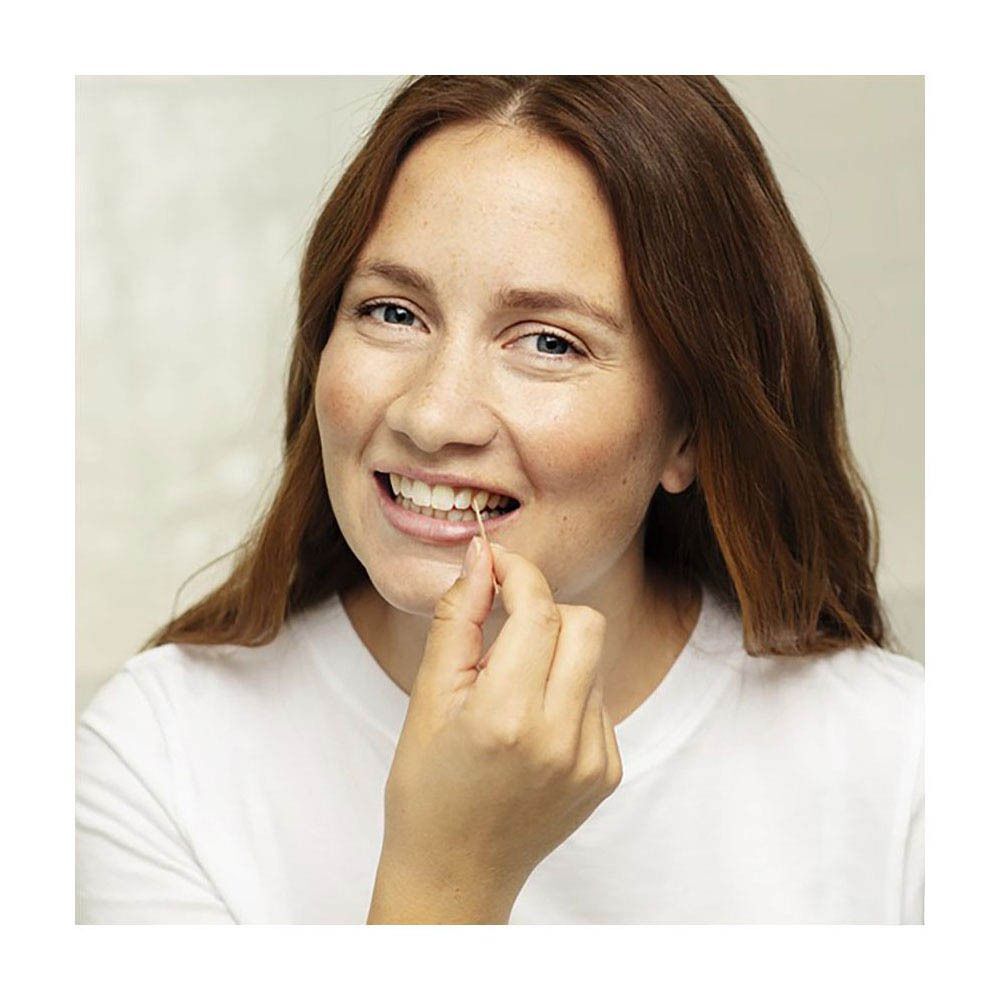 Femme utilisant un cure-dent. Elle le tient entre les dents.