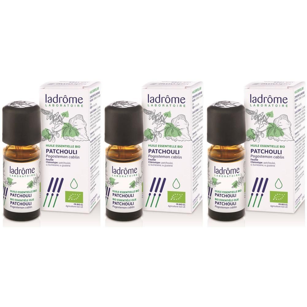 Drie flesjes en verpakkingen van essentiële patchouli-olie. De verpakking toont de merknaam en productinformatie.