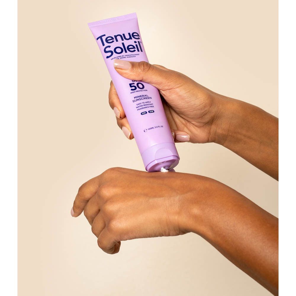 Handen die zonnecrème uit een paarse tube knijpen. Opschrift: Tenue Soleil, SPF 50.