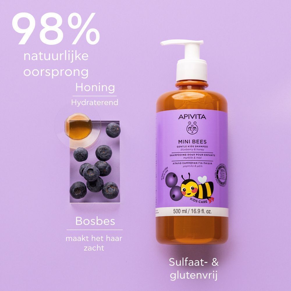Apivita Mini Bees shampoo fles naast bosbessen en honing. Paars etiket, productnaam, bij.