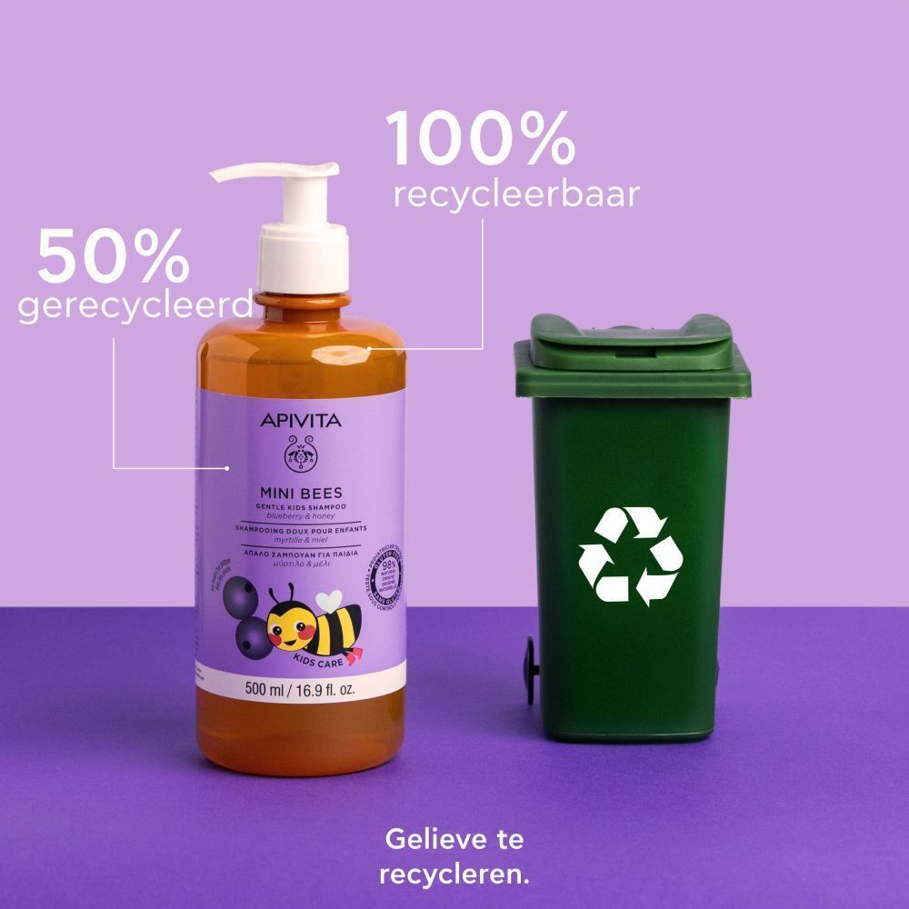 Apivita Mini Bees shampoo fles ligt. Paars etiket, productnaam, bij. Vloeistof stroomt uit de fles.