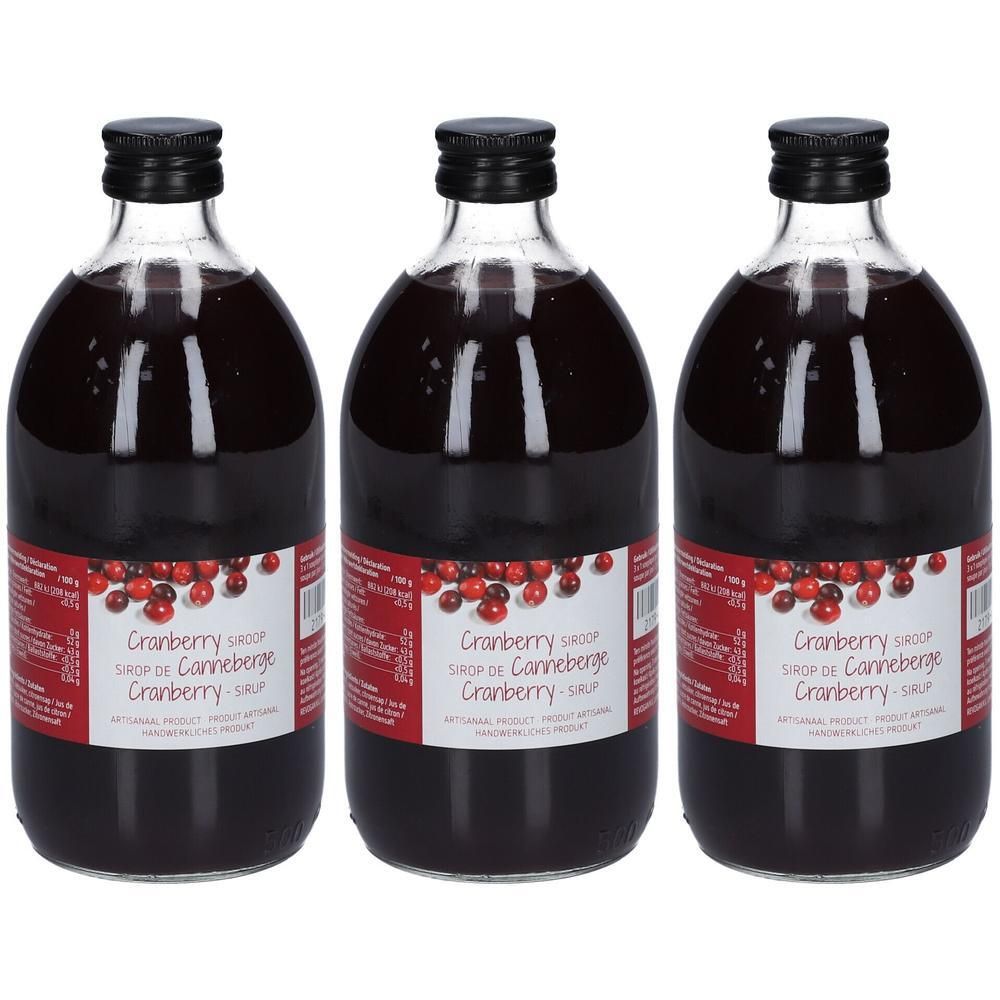 Trois bouteilles de sirop de canneberge. Bouteilles en verre avec bouchon noir et étiquette. Inscription : Cranberry Sirup de Canneberge.