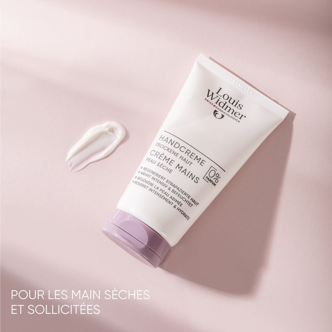 Tube de crème pour les mains, blanc avec bouchon lilas. Inscription: Louis Widmer, Handcrème, Crème Mains. Goutte de crème.