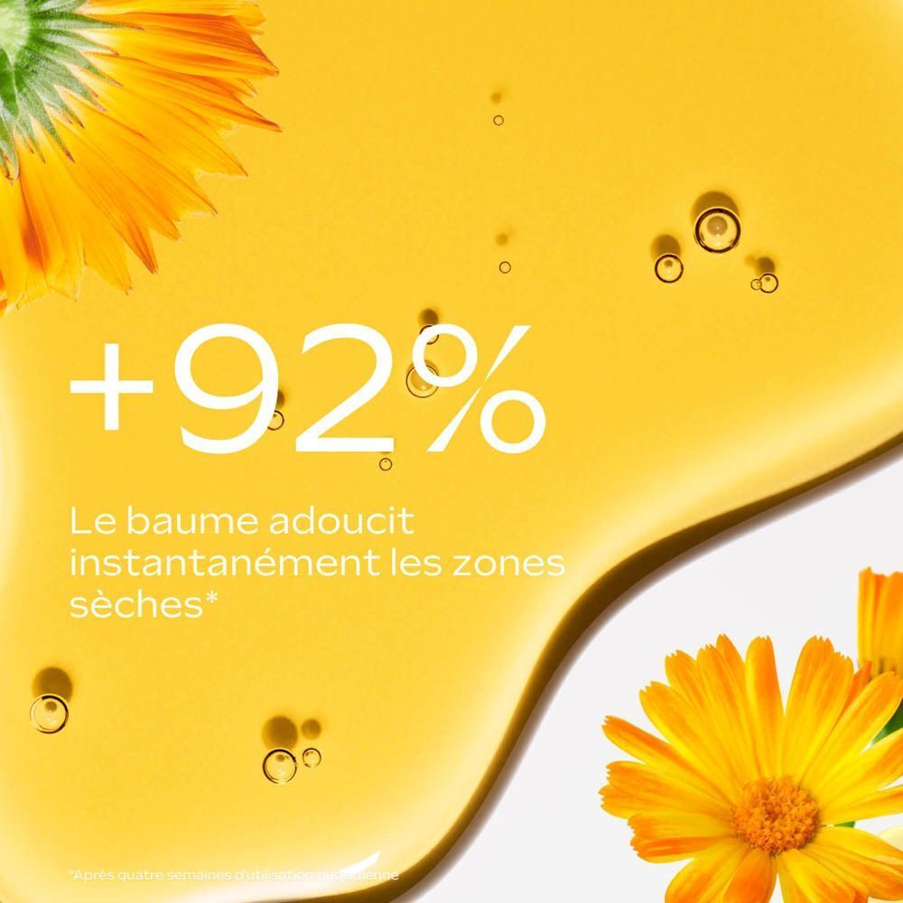 Gros plan sur un liquide jaune avec des pétales. Texte: +92%, Le baume adoucit instantanément les zones sèches.