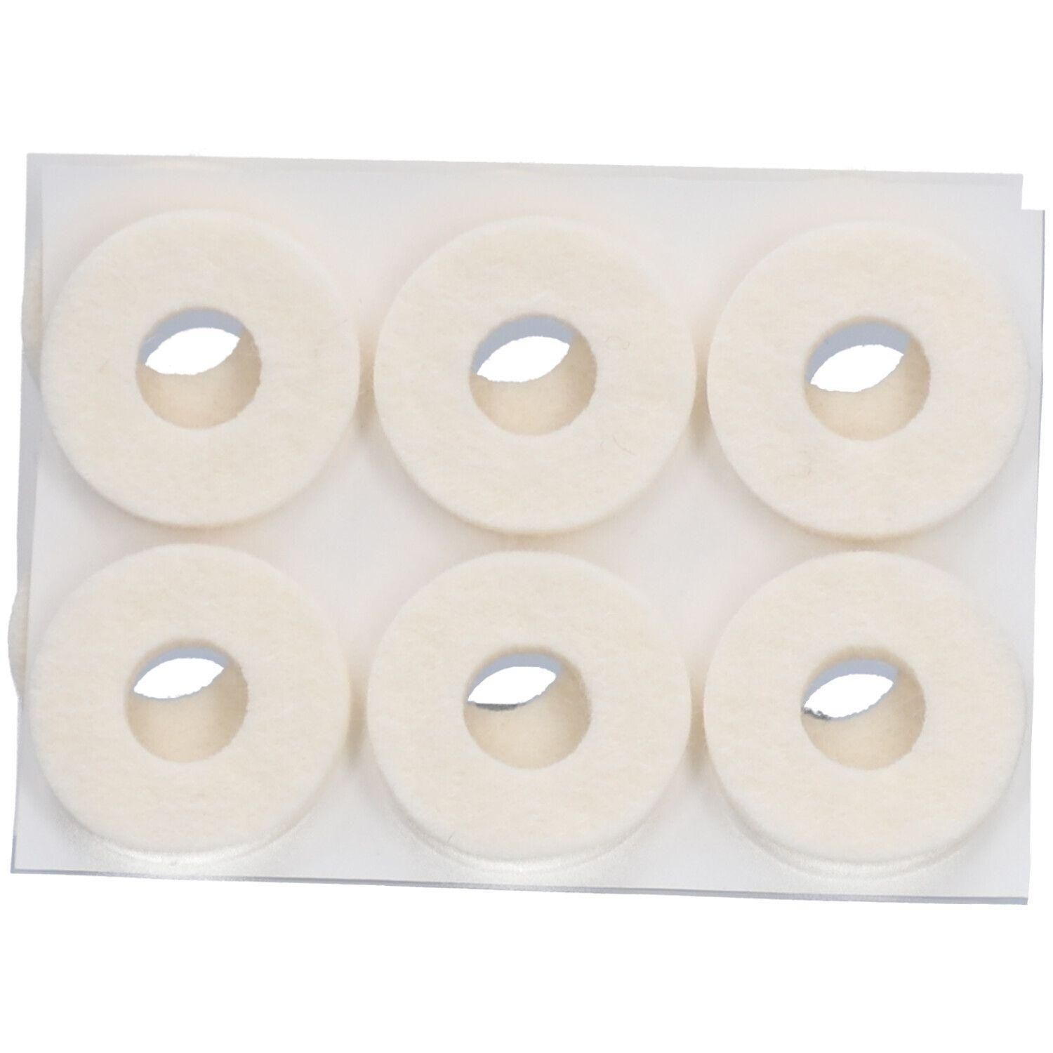 Six anneaux en feutre crème avec trou central, disposés sur une plaque de support rectangulaire.