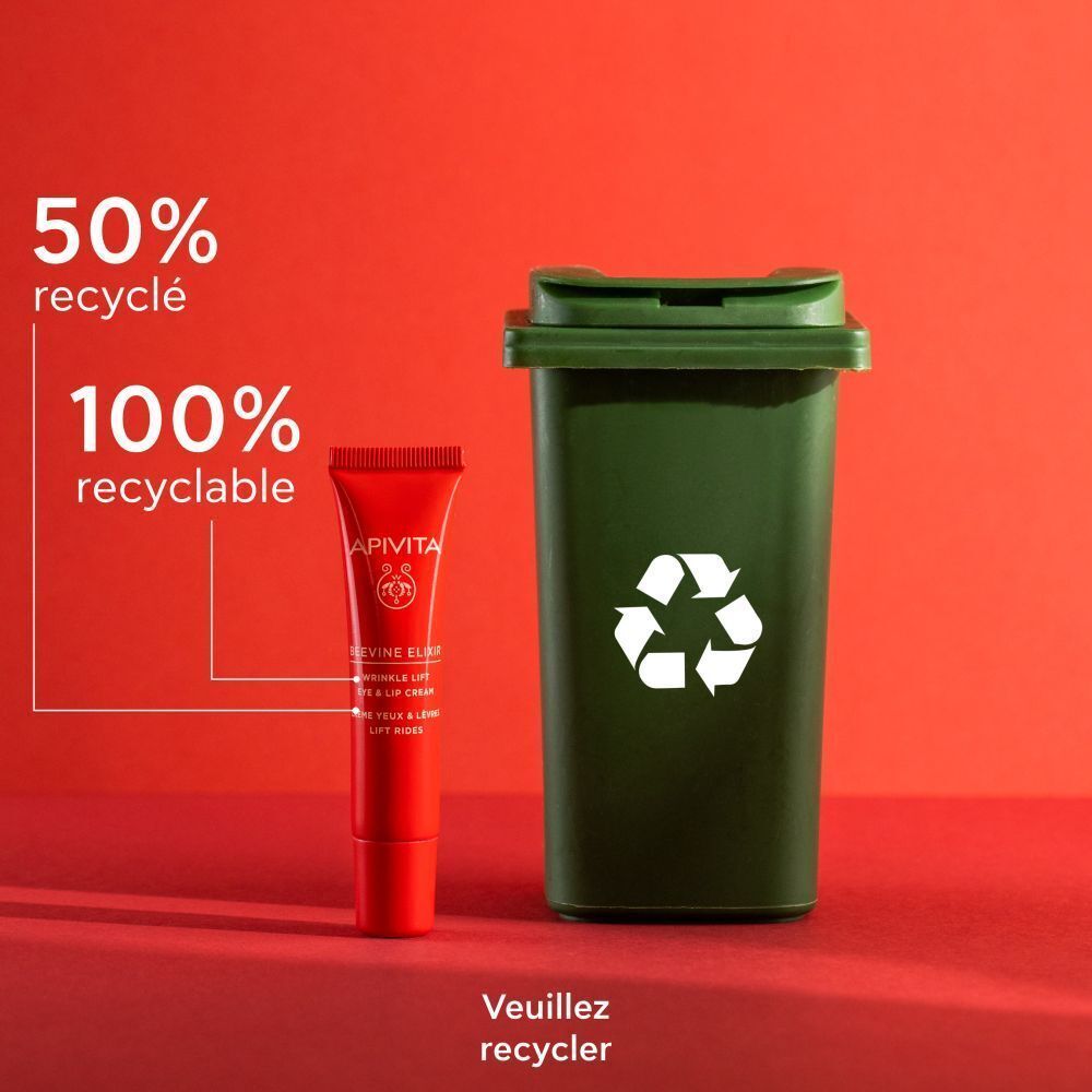 Tube rouge Apivita Beevine Elixir Crème Yeux & Lèvres Lift Rides à côté d'une poubelle verte. Texte: 50% recyclé.