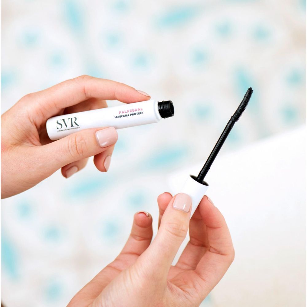 Handen houden een witte mascara tube en een zwarte borstel. Opschrift: PALPEBRAL MASCARA PROTECT en SVR logo.