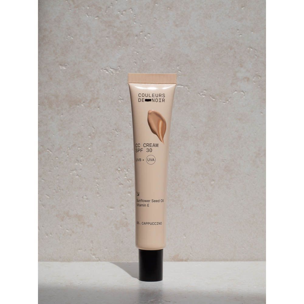 Een tube CC Cream. Op de tube staat: Couleurs de Noir, CC Cream SPF 30, UVB + UVA, 06 Cappuccino. Crèmedruppel.