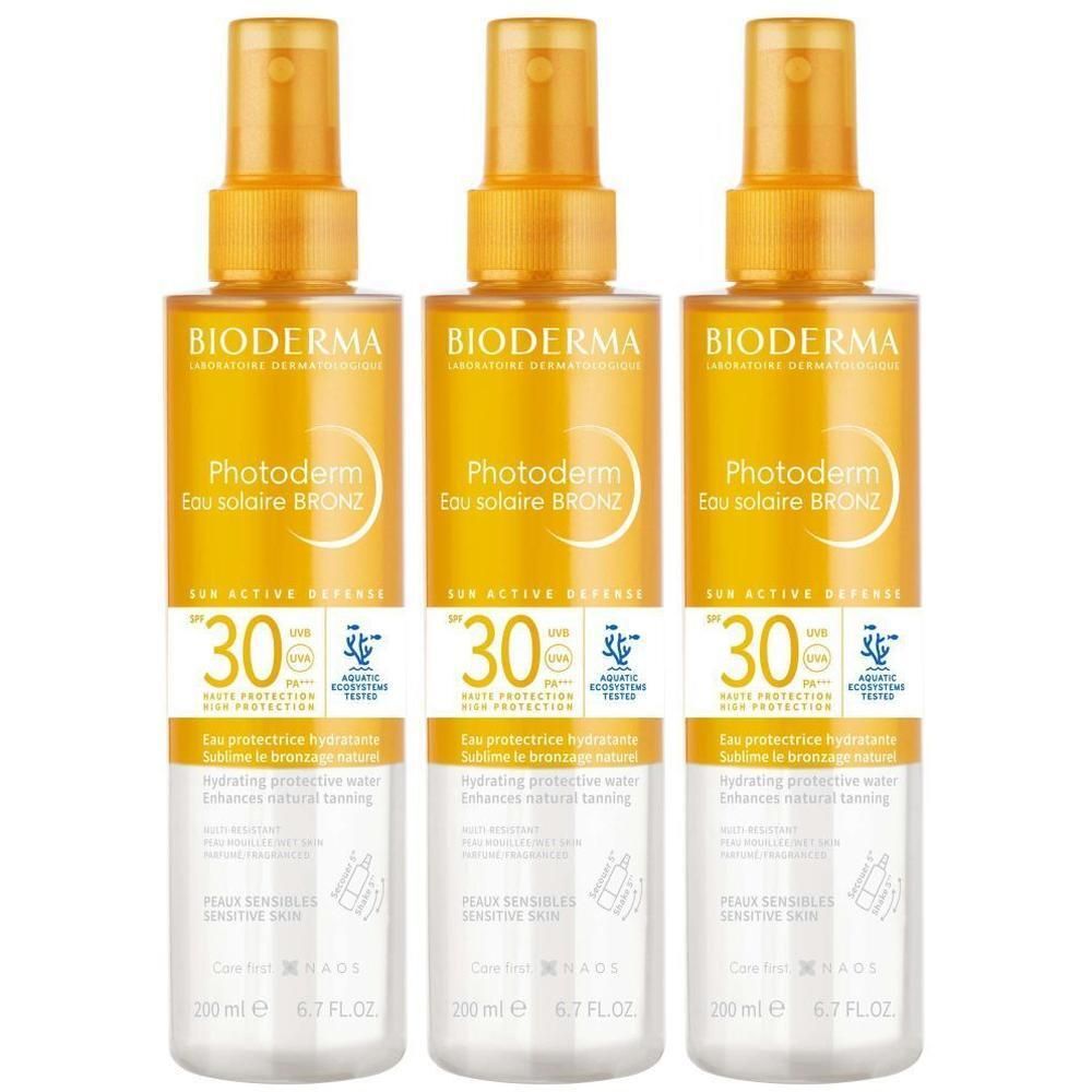 Drie flessen BIODERMA Photoderm Eau solaire Bronz SPF30. Gele vloeistof in transparante flessen met verstuiver. Tekst en logo's.