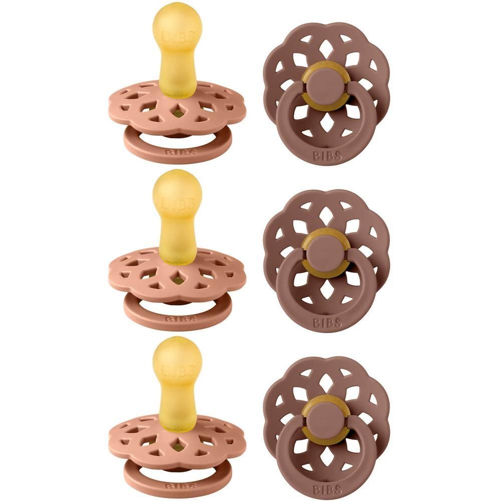 Drie fopspenen, bovenaanzicht. Lichtroze schilden met bloemmotief. Gele latex spenen. Ronde ringen.