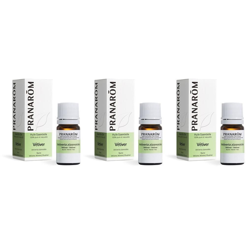 Drie flesjes met witte dop en etiket, naast verpakkingen. Opschrift: Pranarôm. Essentiële olie Vetiver.